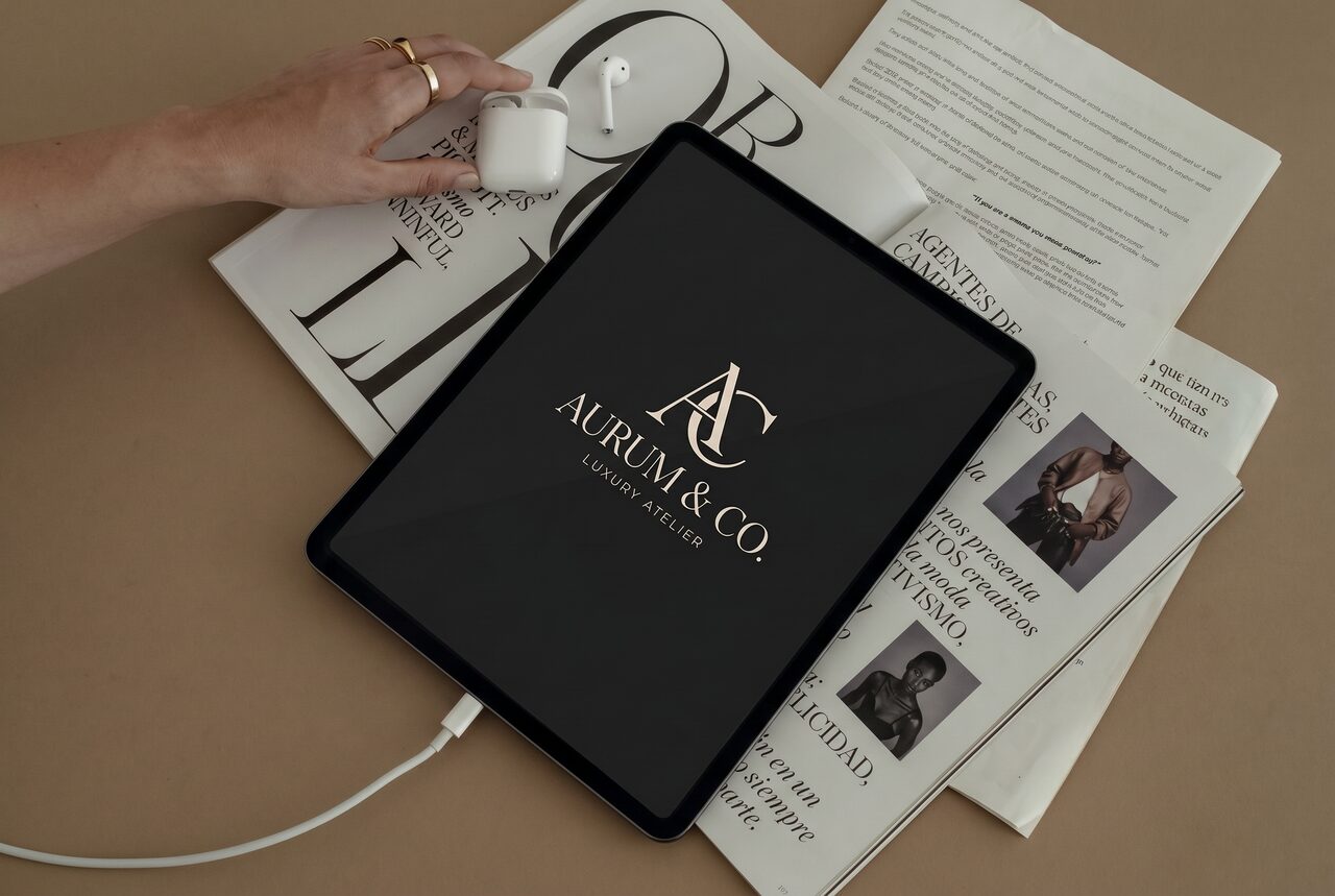 Luxury brand logo presented on a tablet over fashion editorial spreads